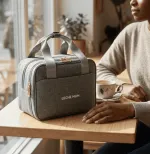 Mum seated beside the grey Leche Mum breast pump bag